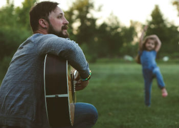 Jason playing guitar while Lily dances.